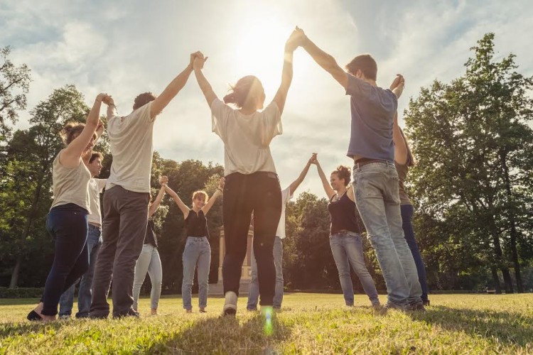 Group of friends at the park holding hands and rise up to the sky.